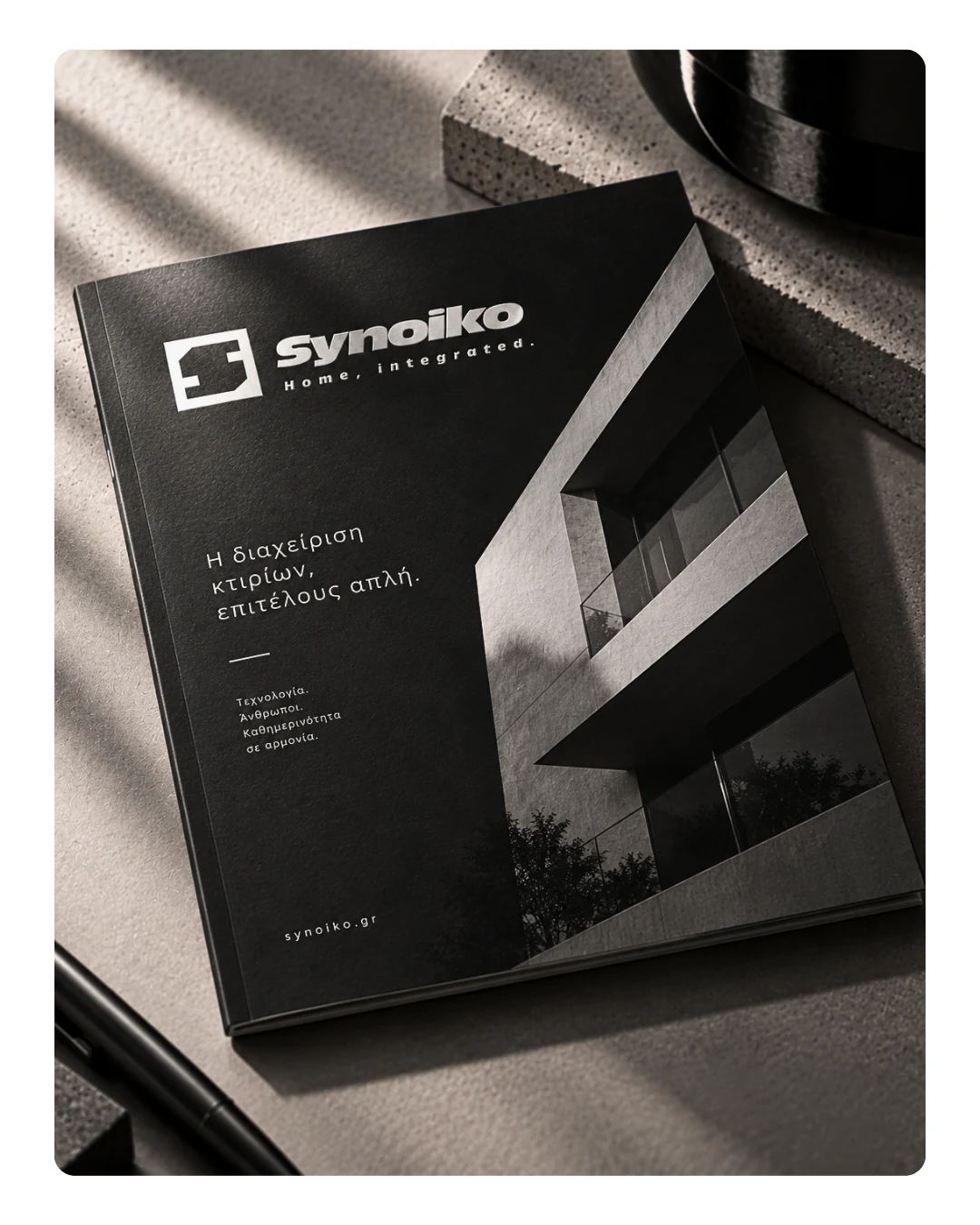 Σκούρο mockup έντυπης παρουσίασης Synoiko με λογότυπο και αρχιτεκτονική φωτογραφία